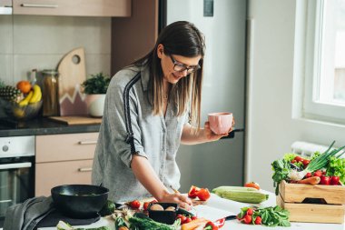 Gülümseyen Kadın Kahve İçiyor ve Evde Yemek Kitabı 'nda Sağlıklı Tarifler Arıyor