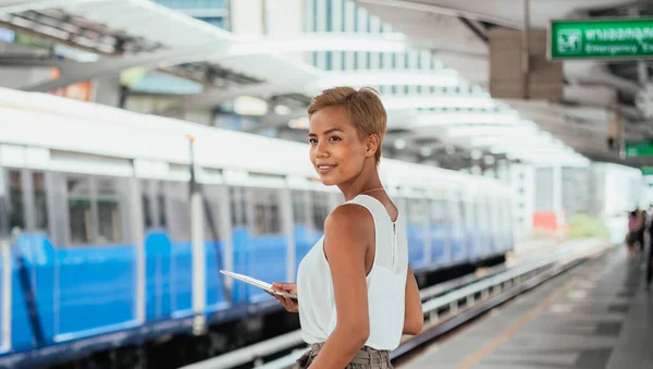Smiling Woman Using Digital Tablet While Standing At Train Station