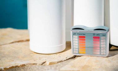 Close up photo of equipment for testing the quality of pool water and chemical cleaning products at the edge of swimming pool