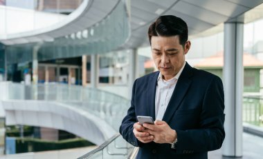 Ciddi Asyalı İş Adamı Ofis Balkonunda Cep Telefonu Kullanıyor