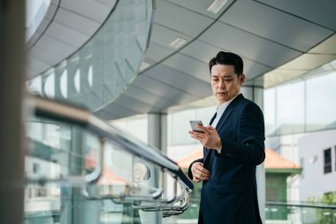 Ofis balkonunda cep telefonu kullanan yakışıklı iş adamının düşük açılı görüntüsü