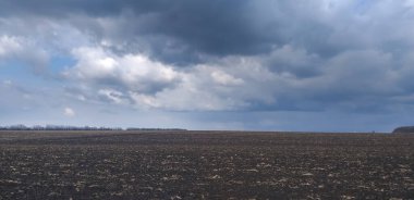 Fırtınalı arazi: Kuru çimen ve fırtına bulutlarının kalıntılarıyla dolu bir alan.