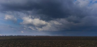 Fırtınalı arazi: Kuru çimen ve fırtına bulutlarının kalıntılarıyla dolu bir alan.