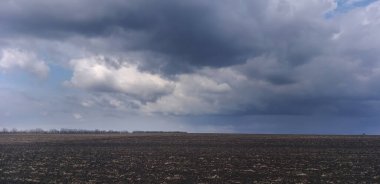 Fırtınalı arazi: Kuru çimen ve fırtına bulutlarının kalıntılarıyla dolu bir alan.