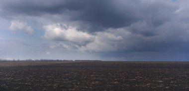 Fırtınalı arazi: Kuru çimen ve fırtına bulutlarının kalıntılarıyla dolu bir alan.