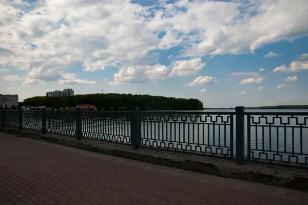 Tranquil Lake Metal Fence Blue Sky White Clouds Houses Distance — Photo