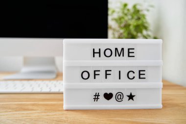 Merkez ofis bir ışık kutusuna yazılır. Işık kutusu ahşap bir masanın üzerinde ve arka planda bir ekran bulanıklaşmış..                               