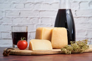  Pecorino veya caprino gibi İtalyan sert peynirleri, sürahi ve geleneksel cam, domates ve kekik ile İtalyan şarabı. Tahtada keklik otuyla dilimlenmiş peynir..                           