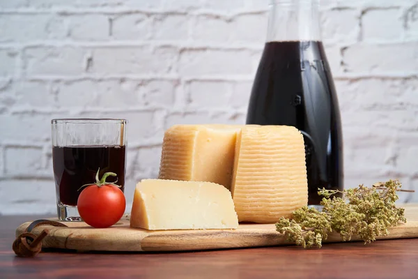  Pecorino veya caprino gibi İtalyan sert peynirleri, sürahi ve geleneksel cam, domates ve kekik ile İtalyan şarabı. Tahtada keklik otuyla dilimlenmiş peynir..                           