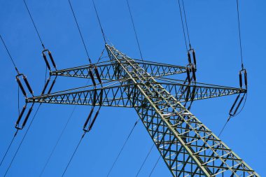 Power pole photographed from below. Blue sky in the background. Electricity for power supply.