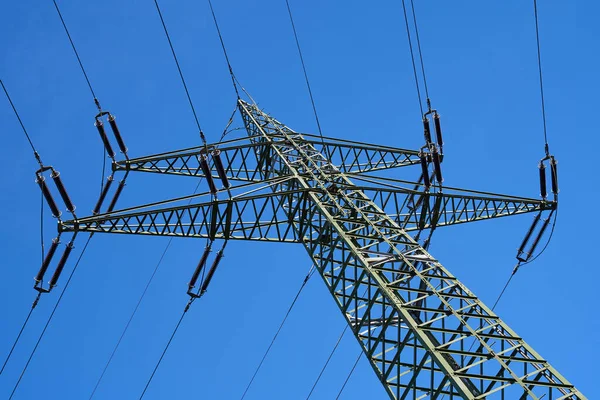 Power pole photographed from below. Blue sky in the background. Electricity for power supply.