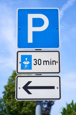 Park diski olan arabaların 30 dakika boyunca park edebileceği bilgisini içeren işaretler. Sol tarafı işaret eden bir işaret var. Üç ayrı trafik işareti.                               
