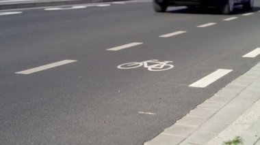 Yolda bir bisiklet yolu ve arka planda bulanık bir araba. Bisikletçiler, arabalar bisiklet yoluna çok yakın sürdüklerinde tehlikededir. Bisiklete karşı araba kullanma, çevre bilinci ve sağlık.