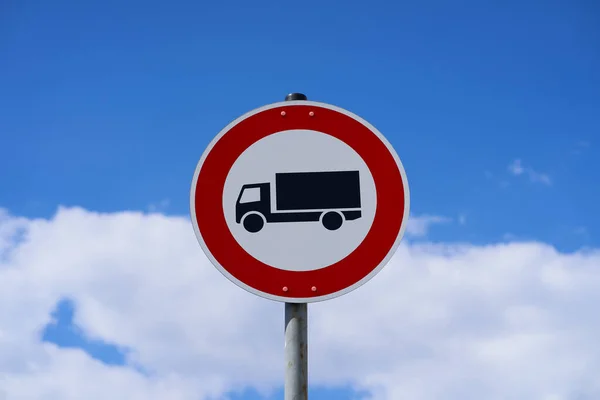 Tabela, kamyonlar için girişin yasak olduğu anlamına geliyor. Kamyonların yolu kullanmasına izin verilmiyor. Tabelada bir kamyon görünüyor. Arka planda gökyüzü ve bulutlar.                           