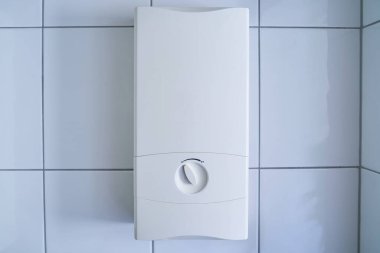 Banyodaki duvarda iki aşamalı su ısıtıcısı asılı. Isıtıcı sadece yüksek enerji maliyetleri nedeniyle birinci aşamada..                               