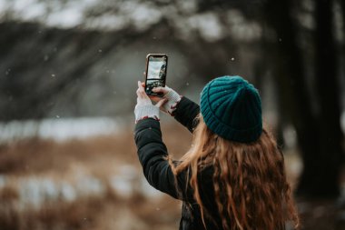 Telefonuyla fotoğraf çeken güzel bir genç kızın sonbahar portresi.
