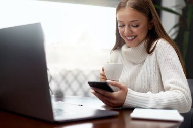 Kafede kahve içerken cep telefonu kullanan mutlu güzel kız.