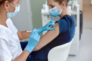 Kadın doktor ya da hemşire hastanın omzuna aşı ya da aşı yapıyor.. 