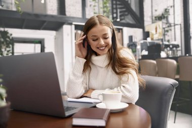 Masada oturup dizüstü bilgisayar kullanan güzel bir kadın. Dizüstü bilgisayarda çalışan kız.