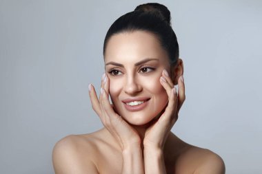 Mükemmel ciltli güzel bir genç kadın. Doğal çıplak makyajlı ve yüzüne dokunan güzel bir mankenin portresi. Spa, Cilt Bakımı.