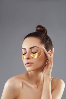 Göz altı yaşlanma karşıtı altın maske takan güzel kadın.