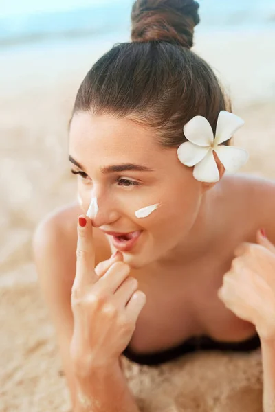 Suntan lotion woman applying sunscreen solar cream. Beautiful happy cute woman  applying suntan cream to her nose.