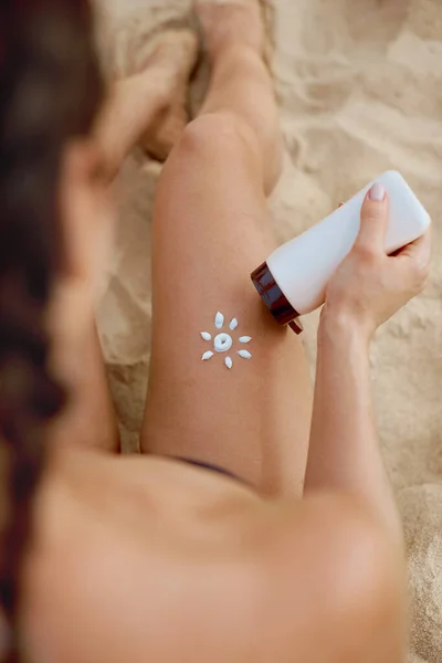 Woman Holding Suntan Lotion And Moisturizing Sunblock. Skin And Body Care. Girl Using Sunscreen To Skin On Legs
