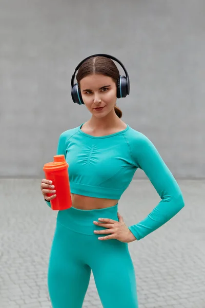 Beautiful Female Runner Standing Outdoors Holding Water Bottle Using Wireless — Stockfoto