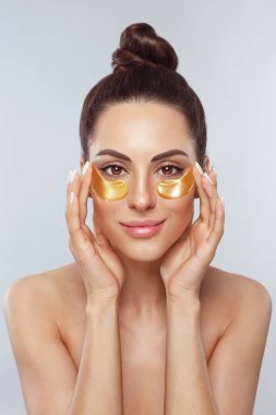 Sağlıklı ve taze ciltli güzel bir kız yüzü. Göz altı kolajen altın pedli bir kadın. Cilt bakımı konsepti, yaşlanma önleyici göz maskesi, altın hidrojel bantlar, göz bakımı, kozmetoloji.