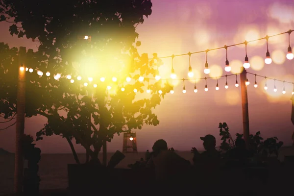 海滨餐馆用黄色线灯装饰日落时模糊的黄昏灯 免版税图库图片