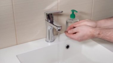 Adam kirli ellerini sabun ve suyla yıkıyor.