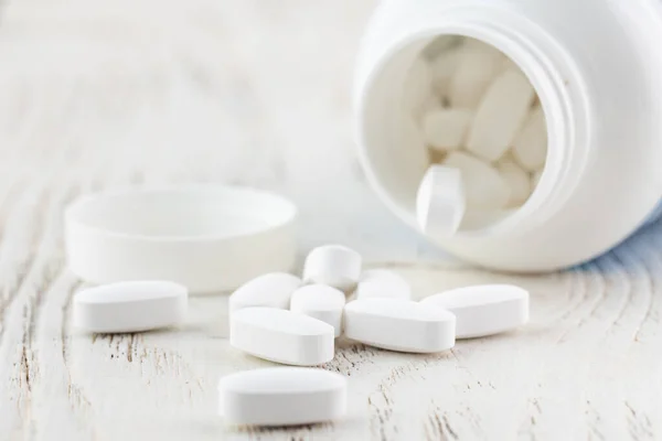 stock image White empty medical jar,scattered tablets in capsules