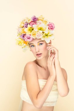 Bahar konsepti, genç kız kafasında çiçeklerle kamera lensine bakar. 