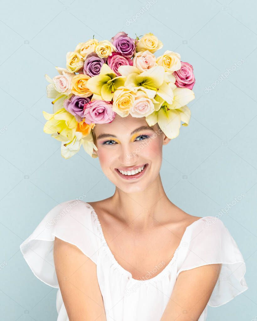 Young girl gently smiles and looks into the camera lens with flowers in the head 