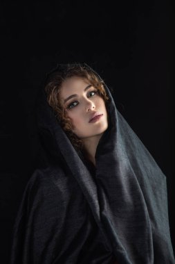 Güzel, yalnız bir kızın dramatik portresi. Gri başörtüsüyle yüzünü stüdyo çekimlerinde koyu bir arka plana kapatmış.