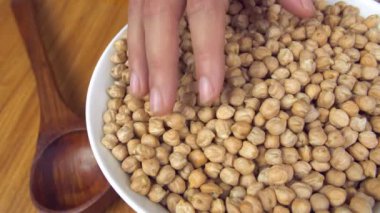 Beyaz kasede servis edilen nohutları kontrol eden bir dişi. Sağlıklı beslenme. Mutfakta Kabuli Channa dolu bir seramik kase. Sağlıklı kalp, kilo kaybı, sindirime yardımcı olur, yaşlanmayı geciktirir.