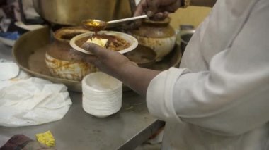 Popüler bir markette bir tabak tereyağlı Chole servis eden bir sokak satıcısı. Eski Delhi 'de küçük bir dükkan. Geleneksel Hint Chole Kulche satıyor. Lezzetli yemekler, baharatlı Chole, hijyenik olmayan Kuzey Hindistan mutfağı.