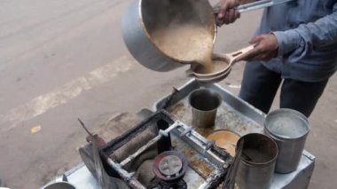Küçük bir dükkanda yerel bir çay satıcısı büyük bir bardakta taze çay servisi yapıyor. Hint çayı Eski Delhi 'de bir çay dükkanında büyük bir Degchi' de hazırlanıyor. Enerji verici, lezzetli, sıcak, atıştırmalık.