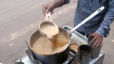 Günlük kıyafet giymiş bir çay satıcısı yol kenarındaki bir çay dükkanında çay hazırlamakla meşgul. Sert aromalı çay / Kadak Chai yol kenarında küçük bir Dhaba - ferahlatıcı içecek, ünlü chaiwallah