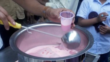 Bir adam bardağa karpuz milkshake dolduruyor. Sokak satıcısı. Kalabalık bir meyve suyu dükkanının önünde sabah ferahlatıcı bir şeyler içmek için bekleyenler var. Sağlıklı beslenme, beslenme, yaşam tarzı.