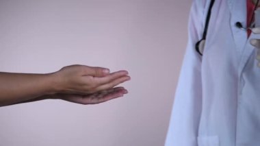 Beyaz üniformalı kıdemli bir doktor hastasının ellerini hastanede sterilize ediyor. Dezenfektan kullandıktan sonra ellerini ovuşturan bir kadın hasta cilt hastalığını ve el yıkamayı iyileştirir.