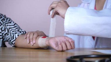 Genç bir hastanın yarasına beyaz bandaj yapıştıran bir hemşire. Ciddi bir kazadan sonra travma uzmanını ziyaret eden kadın hasta - rehabilitasyon, iyileşme, ağrı, travma
