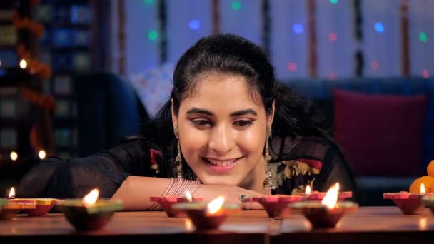 20多岁的小女孩正在观看Diyas灿烂的燃烧 深奥的庆祝活动 一位美丽的女士坐在客厅里 有着节日的背景 印度文化 印度教节日 五彩缤纷的装饰 — 图库视频影像