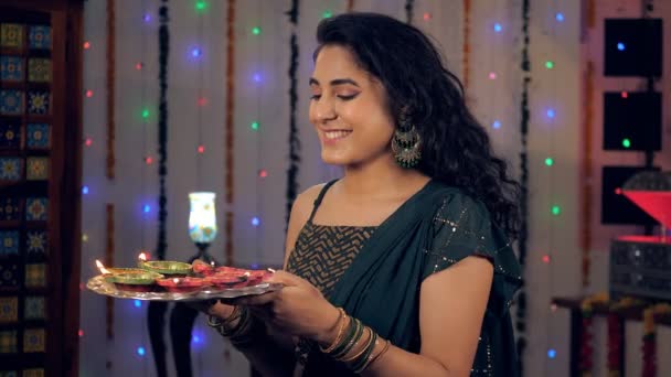 Diwaliで明るく燃えるDiyasのプレートと一緒に立つ魅力的な女の子 カメラを向けながらお祝いの気分できれいな女性 縁起の良い機会に ヒンズー教の祭り ライトのインドの祭り — ストック動画