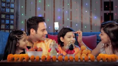 Hintli bir kadın, Diwali Puja 'dan sonra tüm aile üyeleri için kırmızı bir Tika koyuyor. Şenlik döneminde birlikte eğlenen mutlu bir aile - bir Hindu festivali, neşeli bir ruh hali, birliktelik ve bağ.