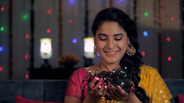 Deepavali için çok renkli dekoratif ışıkları olan güzel bir Hintli kadın. Renkli bir Sari giyen çekici bir kadın festival sezonuna karşı poz veriyor. Uğurlu bir olay, Hindu festivali, aile bir araya geliyor.