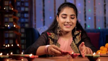 Deepavali festivali sırasında güzel bir Hindu kız mum Diyas yakıyor. Ev yapımı Laddus şenlikli bir arka plana karşı tabakta dururdu. Uğurlu bir olay, Hindu festivali, Hint kültürü.
