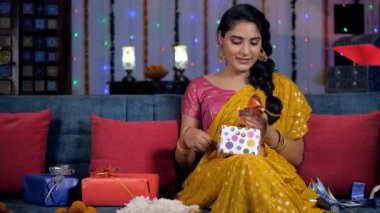 Saree içinde neşeli bir kız arkadaşları ve ailesi için renkli hediye kutuları hazırlıyor. Geleneksel Hint tatlıları ve hediye kutuları bir arada tutulur - Hint kültürü, uğurlu bir olay, Deepavali kutlamaları