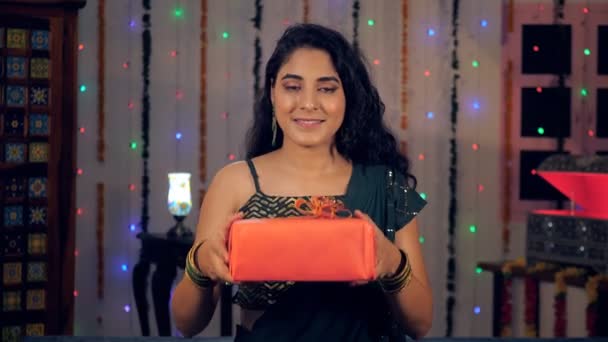 ディワリの機会に彼女のゲストにカラフルな贈り物を提供する若い女の子 インドの光の祭りを自宅で祝う興奮した女性 ヒンズー教の祭り お祝いの気分 お祝いの時間 — ストック動画
