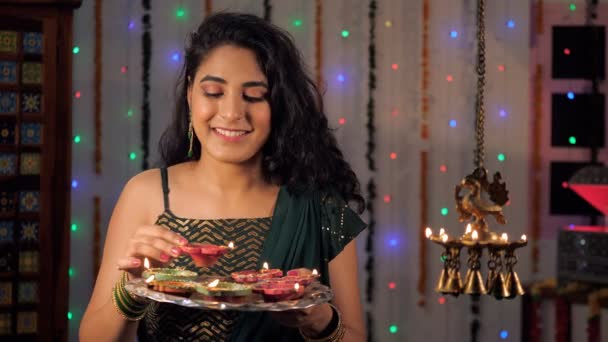 在Diwali的庆祝活动中 一个年轻的女孩抱着一个明亮燃烧的Diya在家里 在喜庆的节日里 一个漂亮的女人在家里心情快乐 一个印度教的节日 一个吉祥的时刻 一个庆祝的时刻 — 图库视频影像